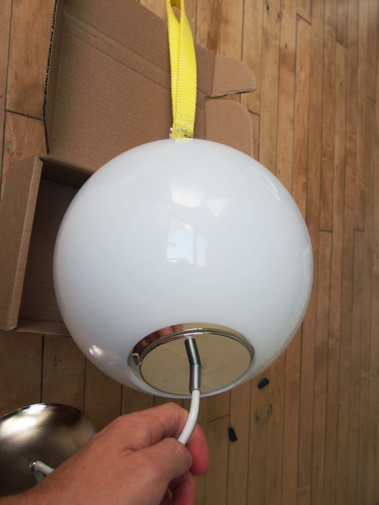 9     Insert the light bulbs in the socket and place everything except the neckless ball holder inside the acrylic ball. Pull the nylon strap through the small hole.