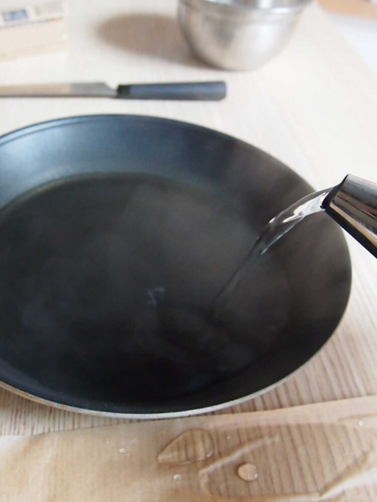 6     Add boiling water to large pan and place the 6in x 6in (15cm x 15cm) square (with coated butcher/baking paper underneath) into the pan to re-heat the plastic.