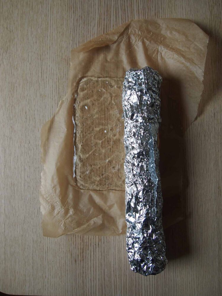 7     Place the end of the aluminum foil tube onto the 6in x 6in (15cm x 15cm) plastic and roll onto the tube.