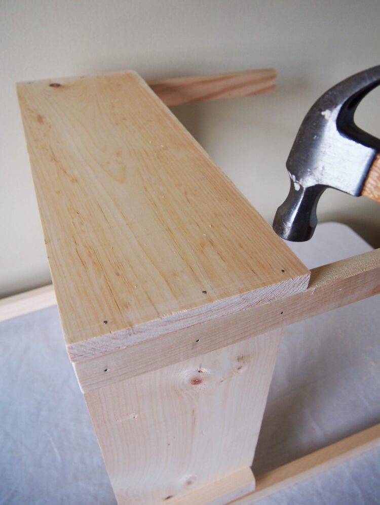 11     Align the end of the 19.5in (50cm) long piece with the side of the chair leg, and hammer in 3 nails through the chair leg to join the pieces. Repeat on the other end.