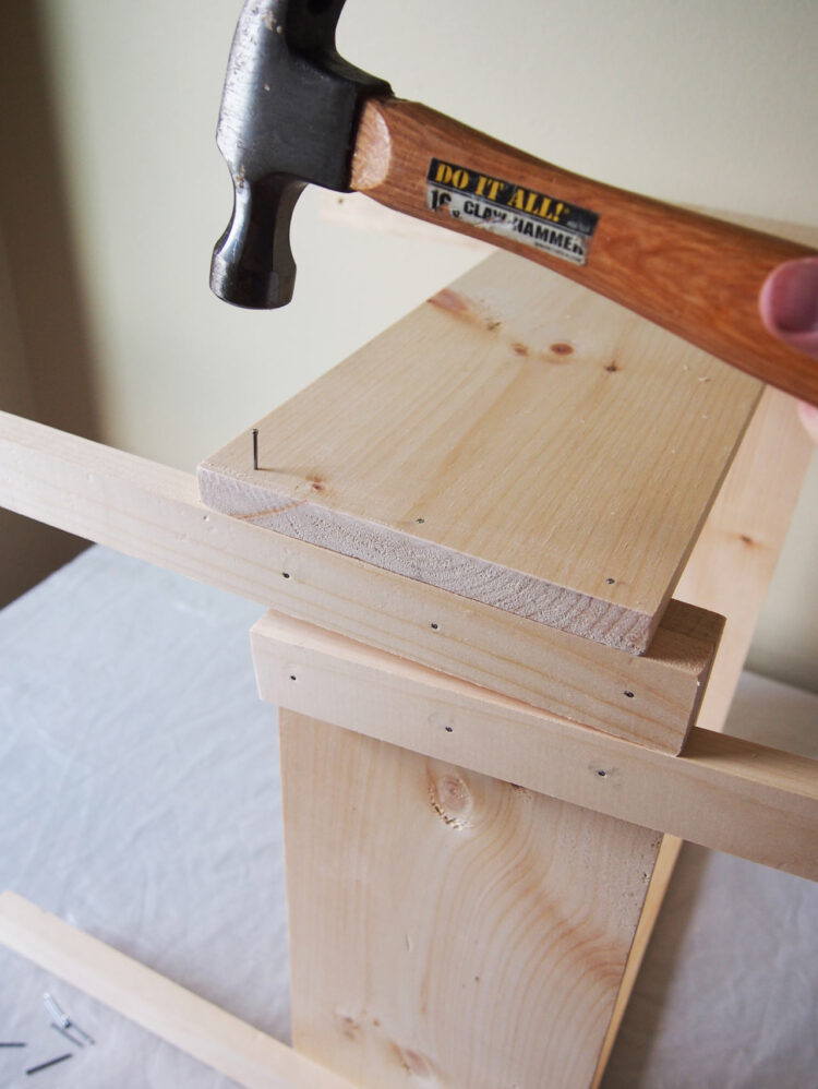 13     Align the end of the 19.5in (50cm) long piece with the side of the chair leg, and hammer in 3 nails through the chair leg to join the pieces. Repeat on the other end.