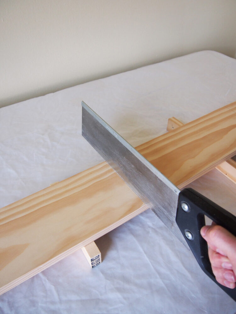 2     Elevate the wood above the table and make cuts according to your measurements with the hand saw.