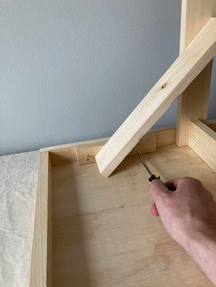 23     Align the structure from steps 13-22 centered on the underside of your table top. With 2 screws, as photographed, attach each 7in (18cm) long piece to the table top.